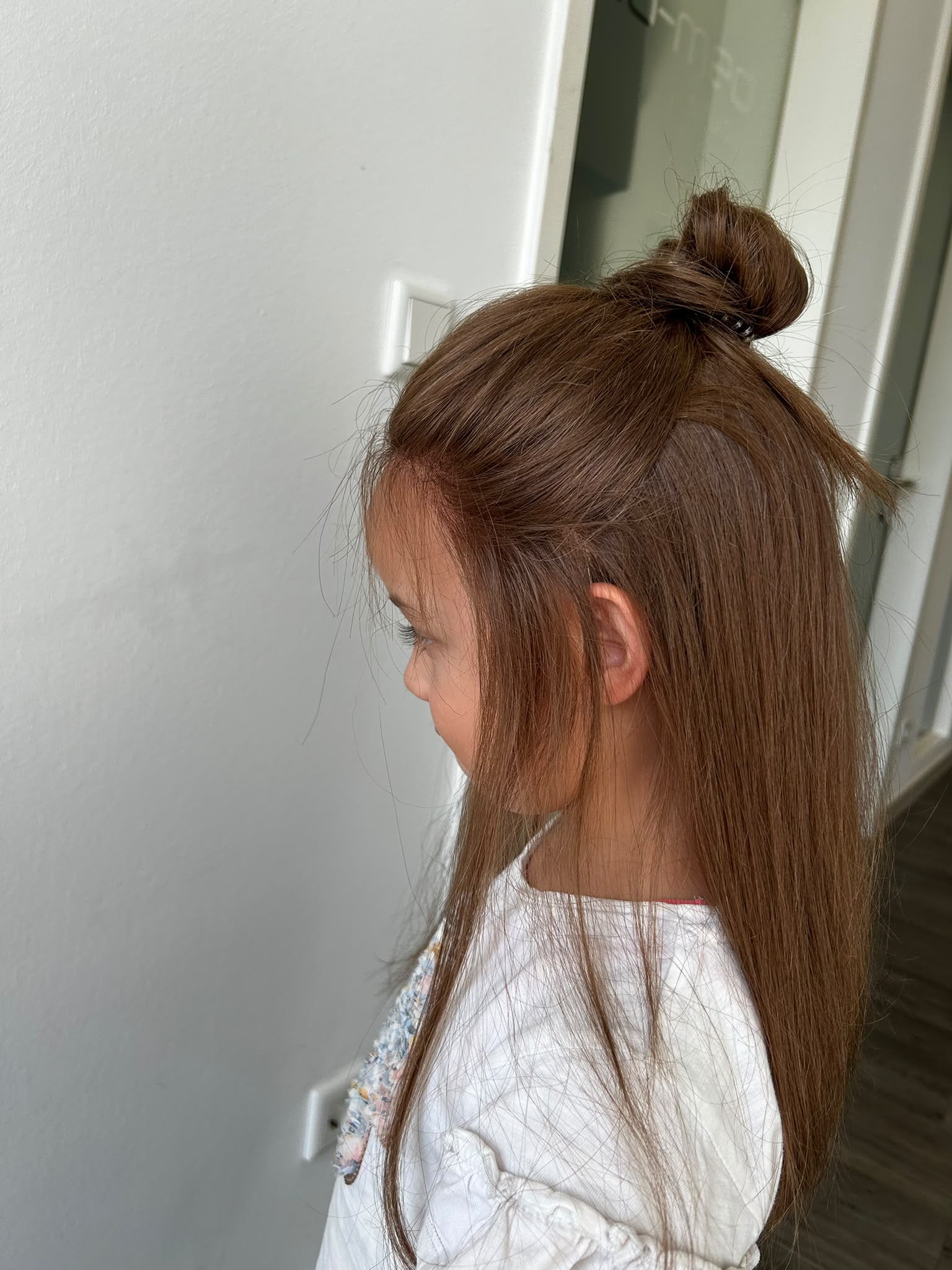 Young HEADS client with a top-knot half-up, side view